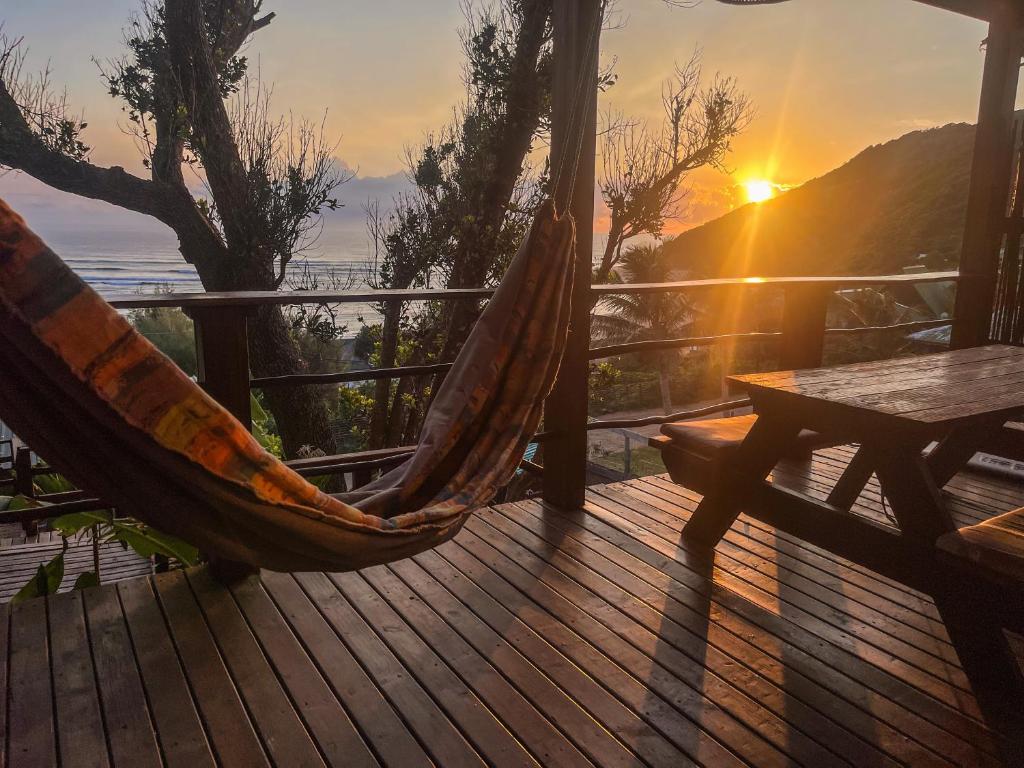 a hammock on a deck with the sunset in the background at Bamboo Room in Ponta do Ouro