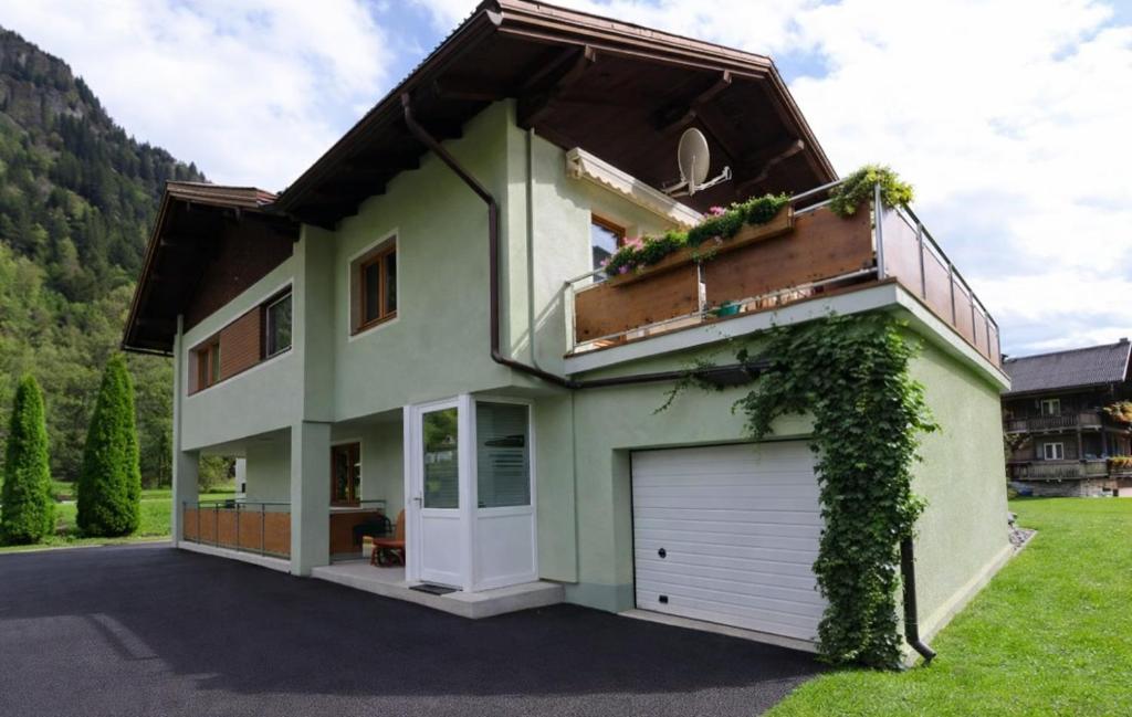 a green house with a white garage at Appartement Dallavia in Sankt Johann im Walde