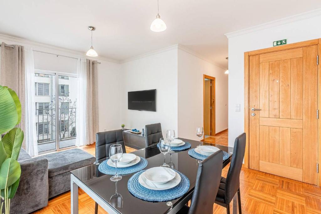 a dining room and living room with a table and chairs at Sapphire Scape Near Airport Madeira Santa Cruz in Gaula