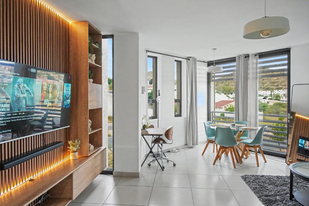 a living room with a tv and a table and chairs at Casa Solis at Wild Olive in Windhoek