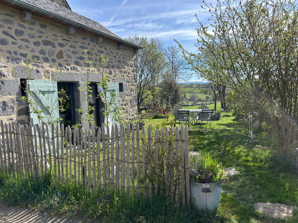 a stone house with a fence in the yard at La Loge de Rose in Peyrelade