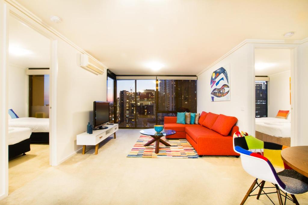 a living room with a red couch and a bed at Exclusive Stays - Southpoint in Melbourne