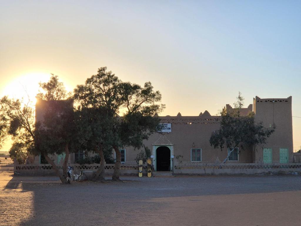 a large building with trees in front of it at Auberge camping la tradition in Merzouga