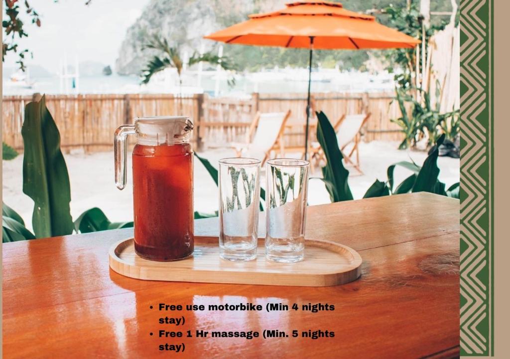 a drink pitcher and two glasses on a wooden table at Balili Villas Free Use Mtorbike During Stay in El Nido