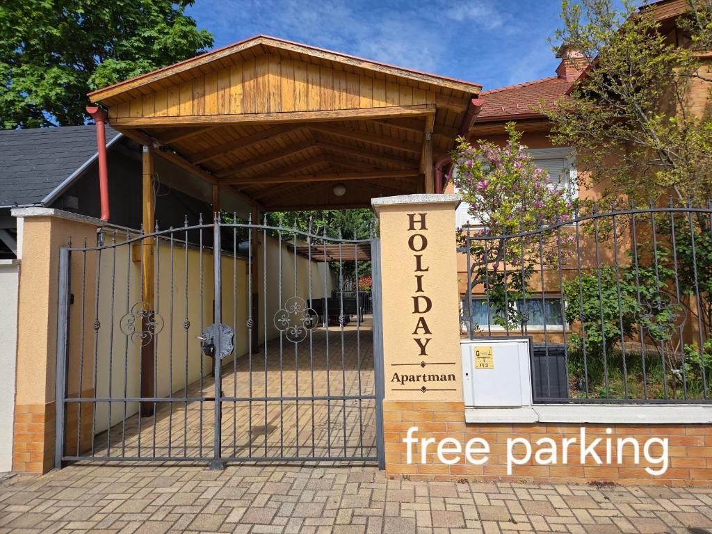 a gate with a free parking sign in front of a building at Holiday Apartman in Kecskemét