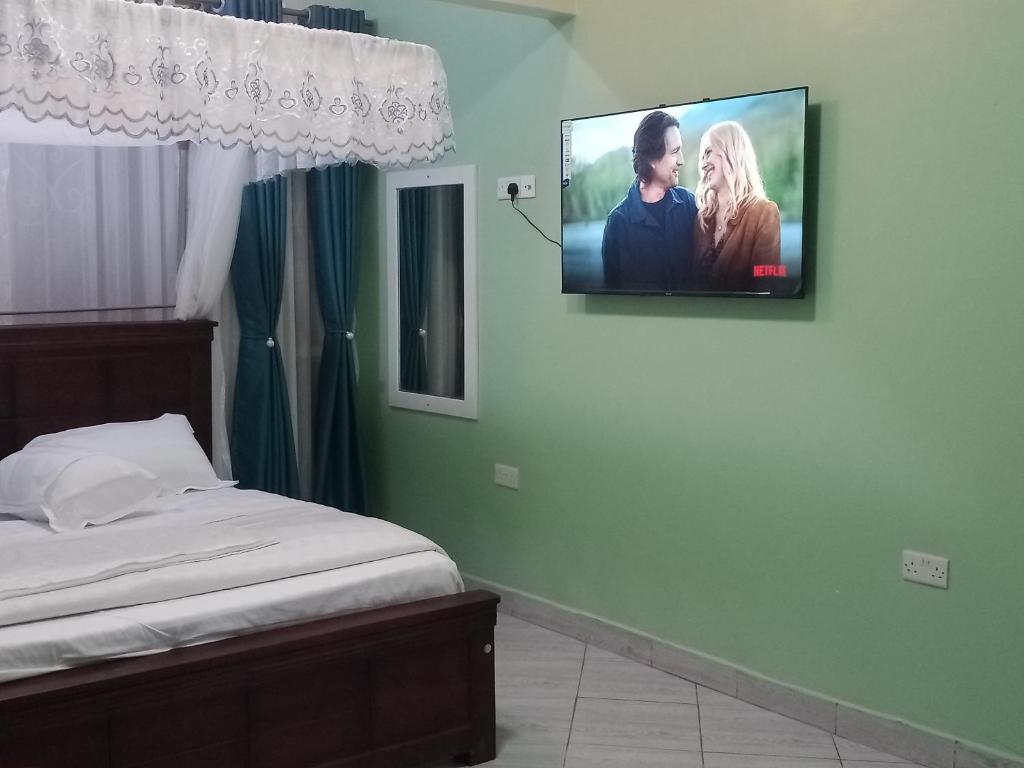 a tv hanging on a wall in a bedroom at BRACCK Suites in Nakwero
