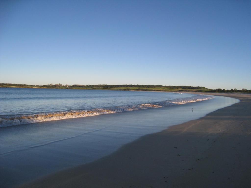 a beach with waves coming in from the ocean at Pelicans Rest Shellharbour in Shellharbour