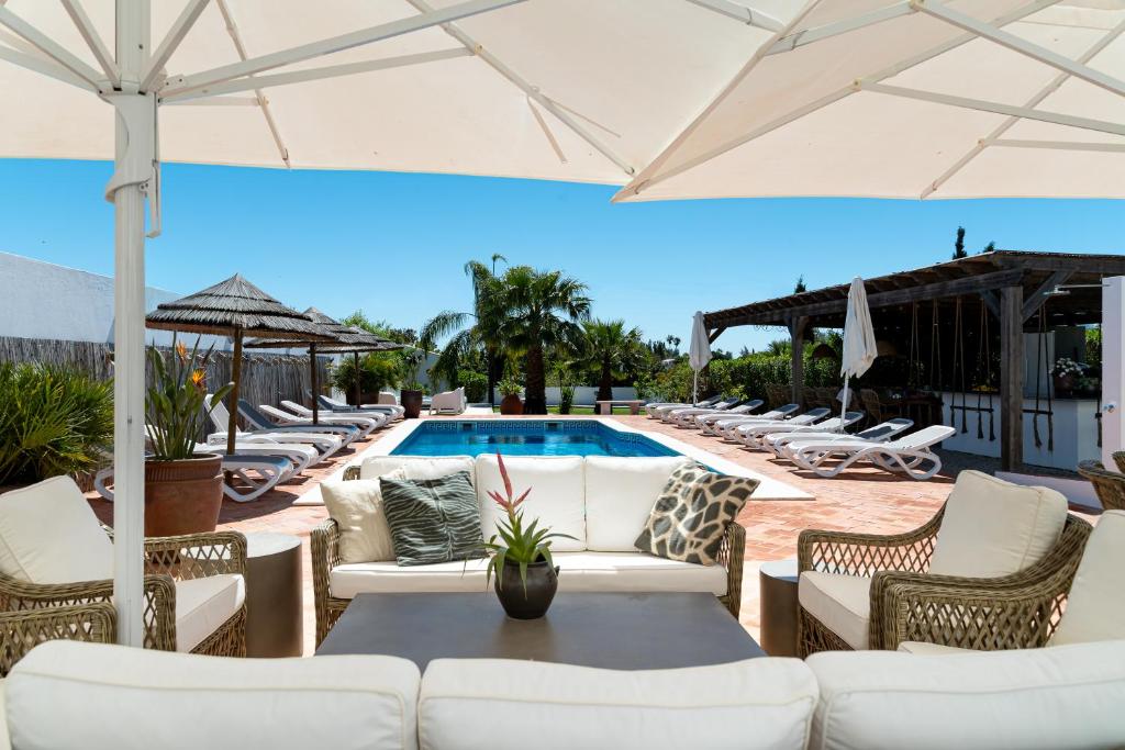 a patio with white furniture and a swimming pool at Quinta do Pedro in Luz de Tavira