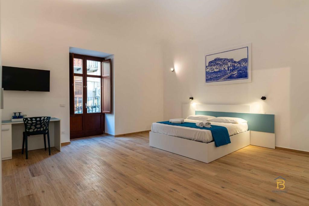 a bedroom with a bed and a desk and a television at Identity By Rentbase in Cefalù