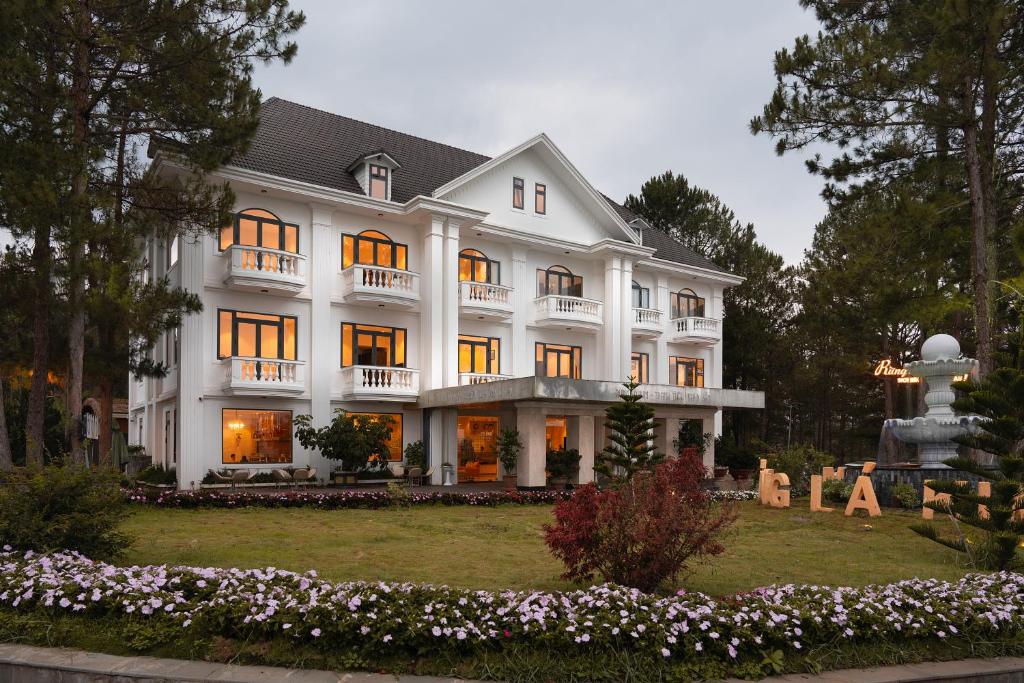 a large white house with a garden in front of it at Rung La Kim Resort in Da Lat