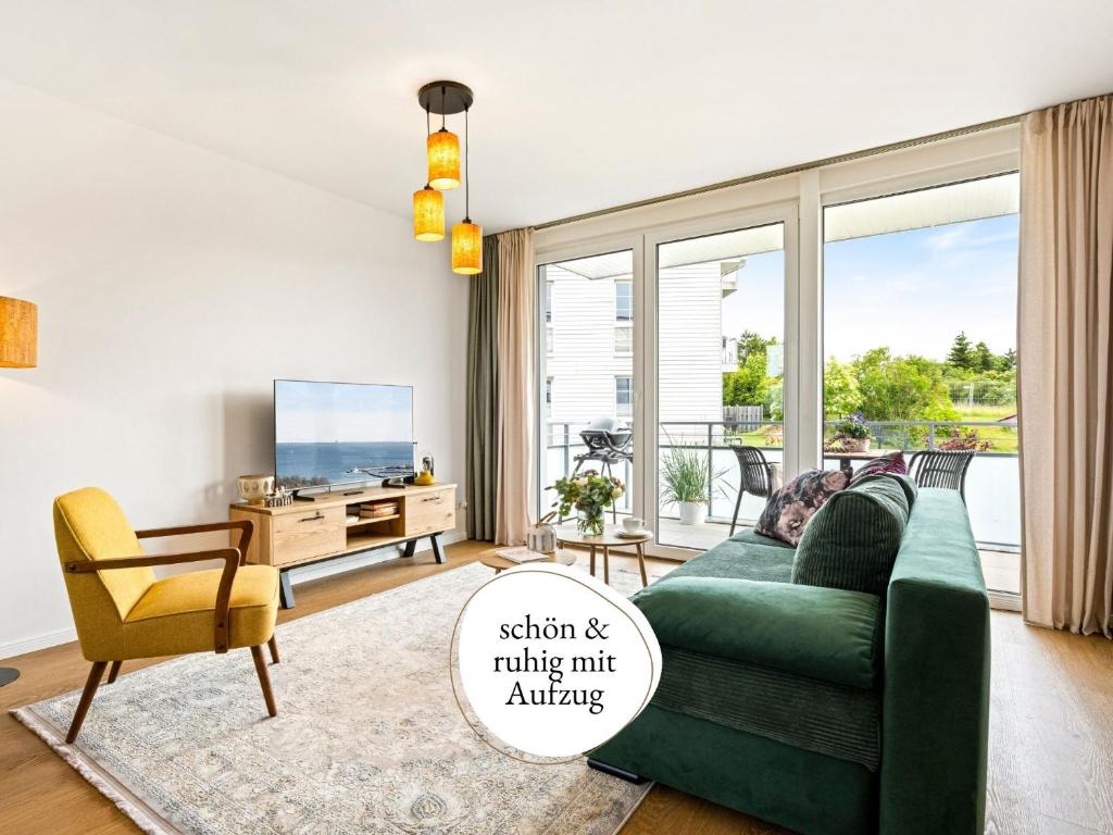 ein Wohnzimmer mit einer grünen Couch und einem Fernseher in der Unterkunft Fewo Edel&Liebe Neubau mit Fahrstuhl, Parkplatz, Balkon, W-lan, ruhige Lage, Einkaufsmöglichkeiten 500m entfernt in Grömitz