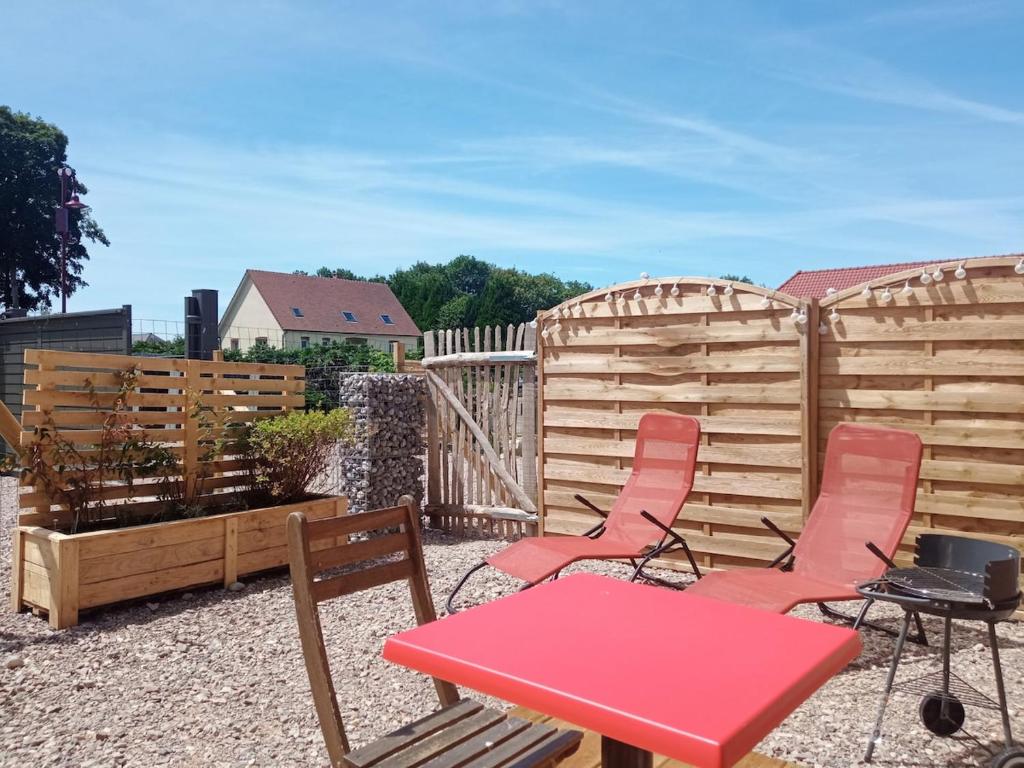 a patio with a table and chairs and a fence at Gîte du Bois de Drancourt in Drancourt