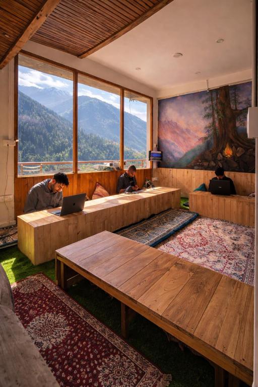 a room with couches and a table with a laptop at Jibhi Emberwood in Jibhi