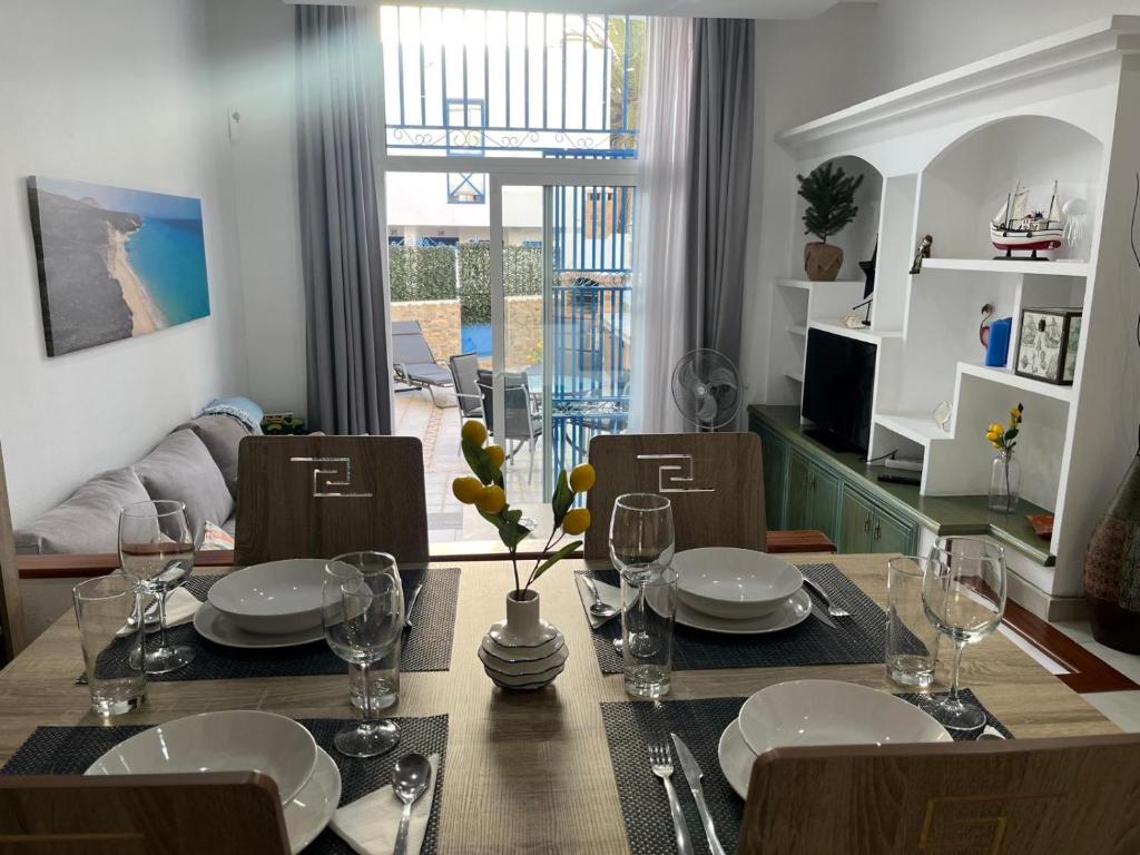 a dining room with a table with plates and wine glasses at C&M Dream House in Morro del Jable