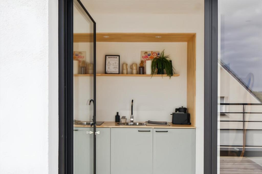 a kitchen with white cabinets and a sink at Escale Doullennaise - Appartement neuf avec terrasse in Doullens