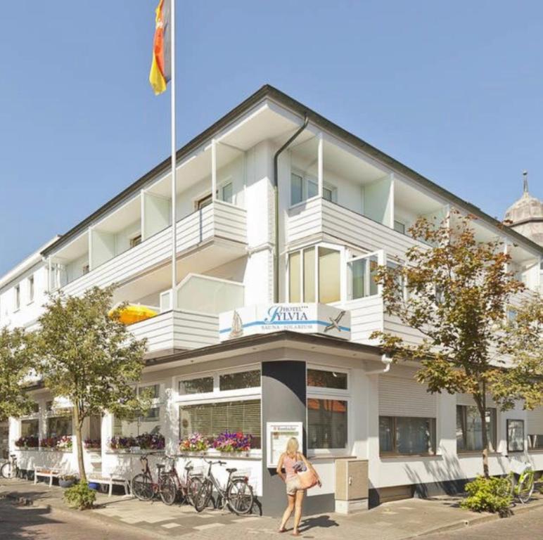 a woman standing in front of a building at Hotel Sylvia in Norderney