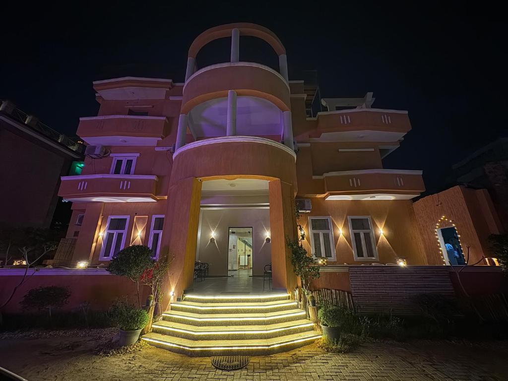 a pink building with stairs in front of it at night at Tutankhamun Pyramids boutique in Cairo