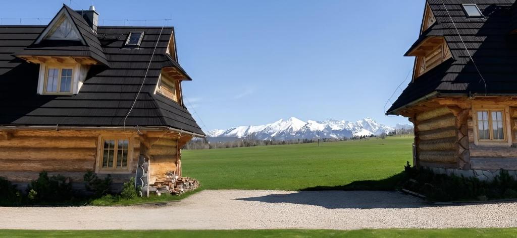 a log house next to a green field and mountains at Sun&Ski Maciejówka Domki Białka Tatrzańska in Białka Tatrzańska