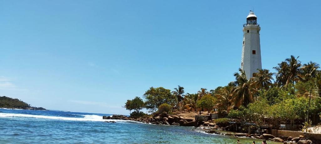 a lighthouse on a beach with people in the water at Lighthouse Peacock Villa in Dondra West