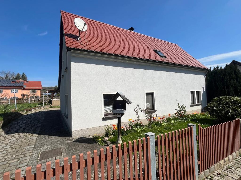 a white building with a red roof next to a fence at Ferienhaus Kluttig in Hörnitz