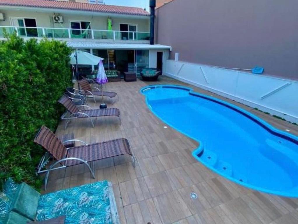 a swimming pool with chairs next to a building at pousada das manas in Torres