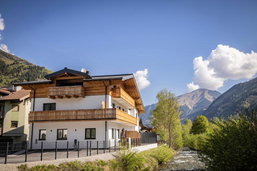 a house in the mountains with a river in front of it at RIVERSIDE RAURIS APARTMENTS in Rauris