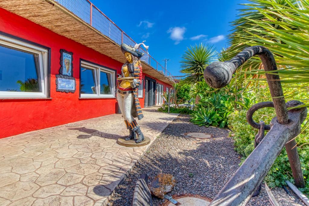 a statue of a man standing next to a red building at Hotel Rural Los Piratas in Tijarafe