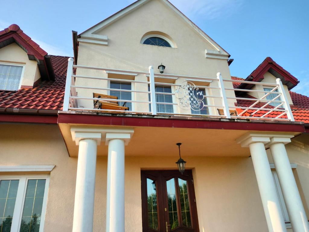 a house with a balcony on top of it at Dworek Zielone Wzgórza Nad Jeziorem in Postawele