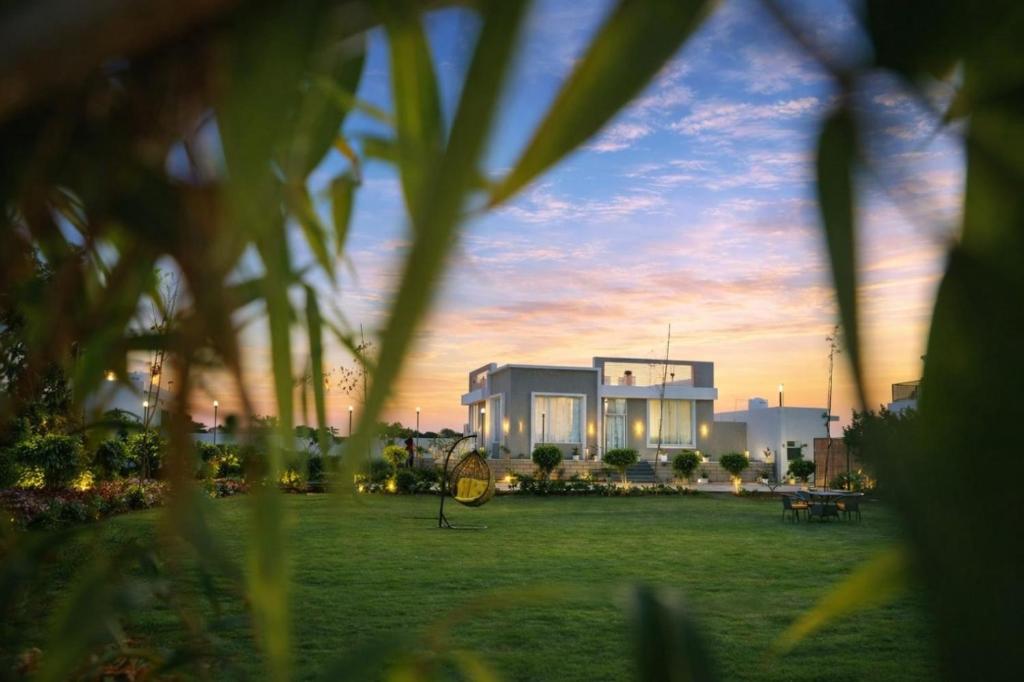 a building in a field with the sunset in the background at Summit Springs Resorts in Bagru
