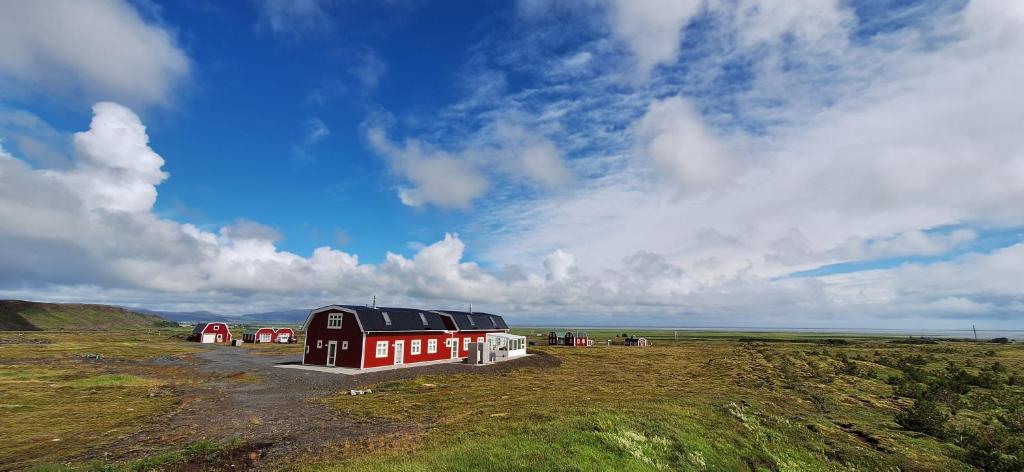 a red and white building in a field with a sky at Cottage in the middle of nowhere in Ölfus