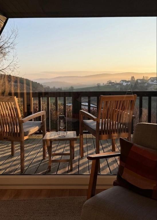 two wooden chairs and a table on a balcony at Designer chalet with gorgeous Eifel panorama in Kerschenbach
