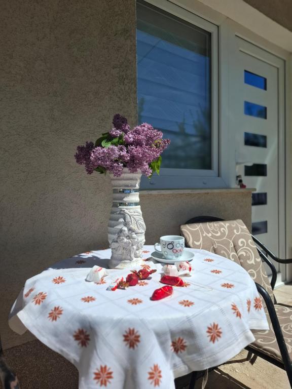 a table with a vase with purple flowers on it at AMADA apartman in Vranješ