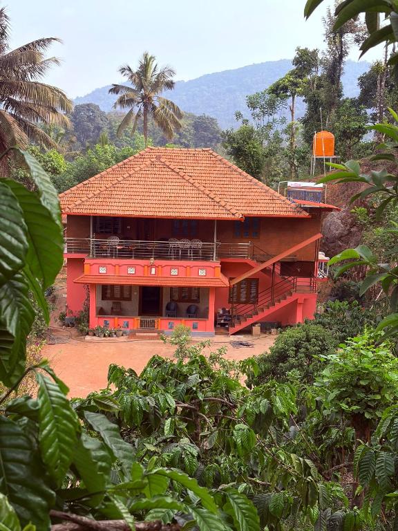 a red house with an orange roof at Dishaa Estate View Home Stay in Madikeri
