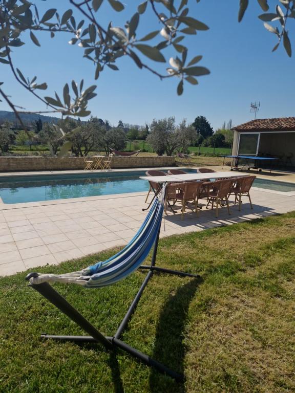 a hammock sitting in the grass next to a pool at Villa à charleval en campagne avec piscine 14 couchages in Charleval