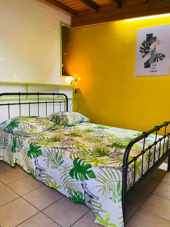 a bed in a room with a yellow wall at Chambre indépendante in Basse-Terre