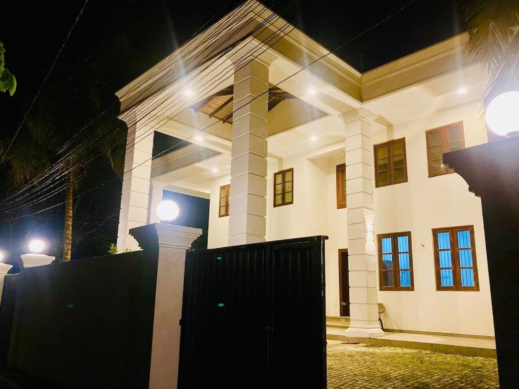 a large white house with a gate at night at Sky Mansion Athurugiriya in Athurugiriya