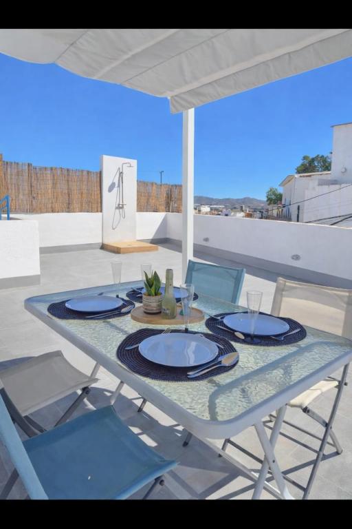 a table with plates and chairs on a patio at Casa Del Sol in Águilas