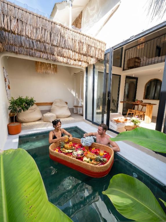 a man and woman sitting in a pool with a tray of food at Casa pumara loft in Kerobokan