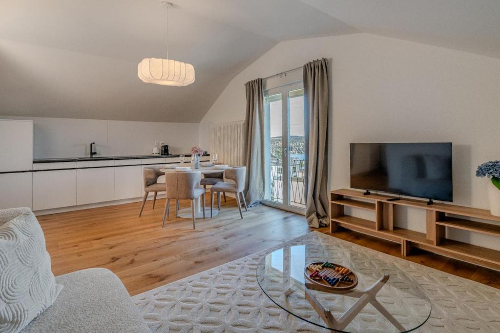 a living room with a kitchen and a table with a television at Vanilla Suite · Kilchberg in Kilchberg