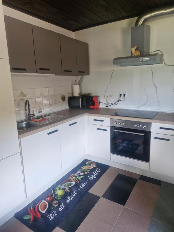 a kitchen with white cabinets and a kitchen rug on the floor at Mirna zelena dolina in Šentilj