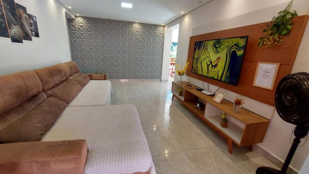 a living room with a couch and a tv at Recanto da Saudade, 3 Quartos, Piscina, Churrasqueira in Boituva