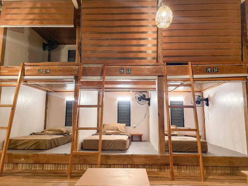 a room with three bunk beds and a table at Bisita Hostel in Siquijor