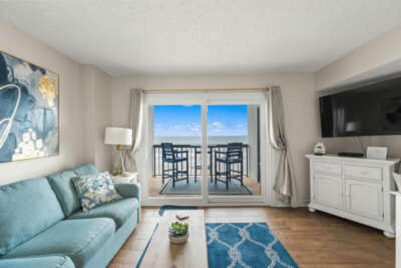 a living room with a blue couch and a balcony at Oceanfront Condo, Steps to the Beach in Myrtle Beach