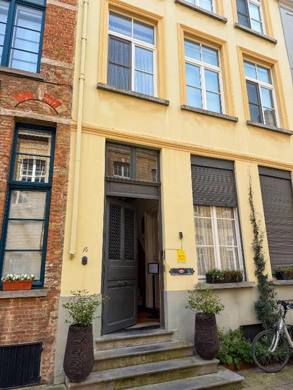 a yellow house with a black door and a bicycle at Clemanbruges in Bruges