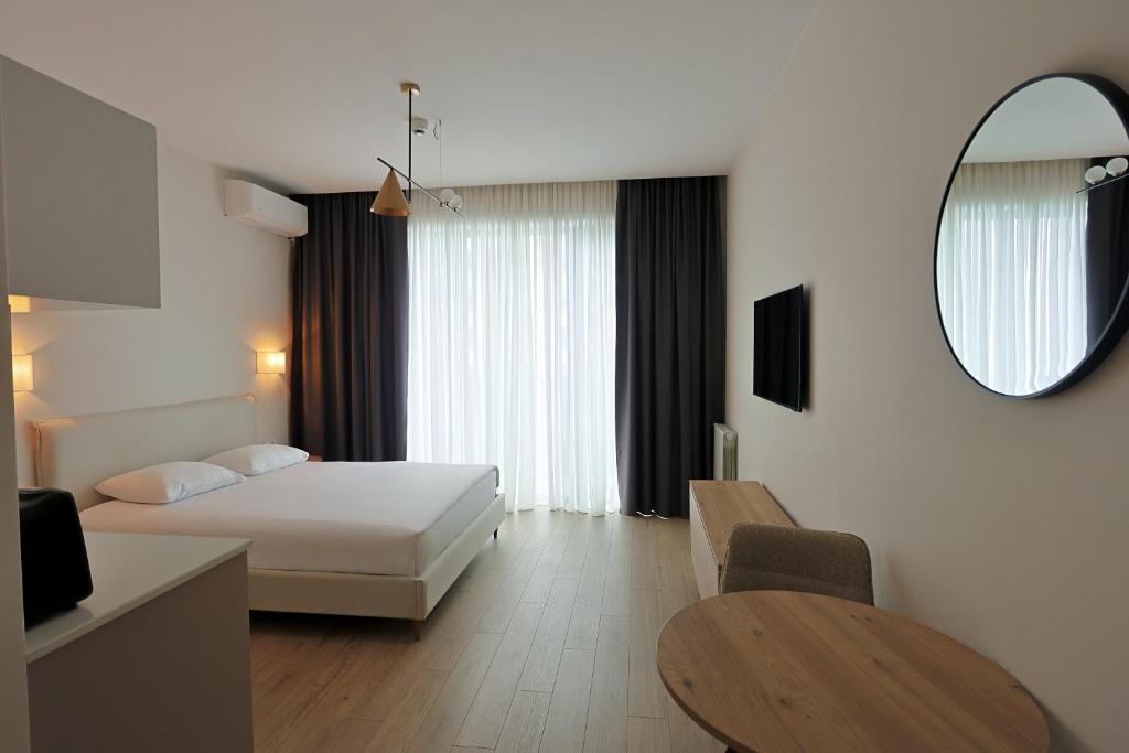 a bedroom with a bed and a mirror and a table at Mira Seaview Studio Apartment in Batumi in Batumi