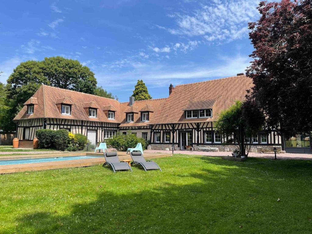 a house with two lounge chairs in the grass at La Maison Maya Normandie in Saint-Éloi-de-Fourques