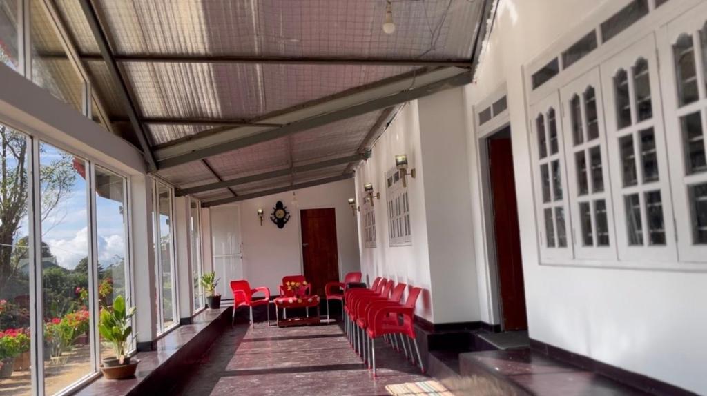 a room with red chairs and tables and windows at Madu Guest in Nuwara Eliya