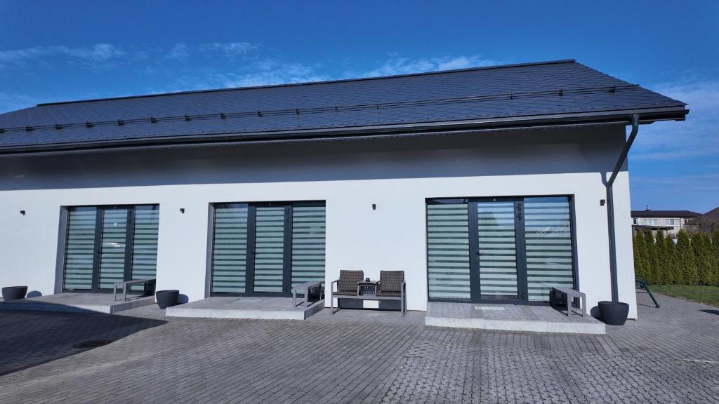 a white building with three windows and a patio at Bele Lofts in Karmėlava
