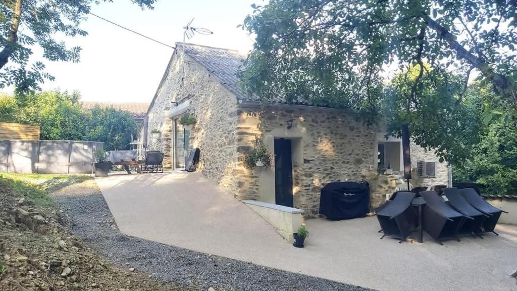 a stone house with chairs in front of it at La Grange du Pradel in Montredon-Labessonnié