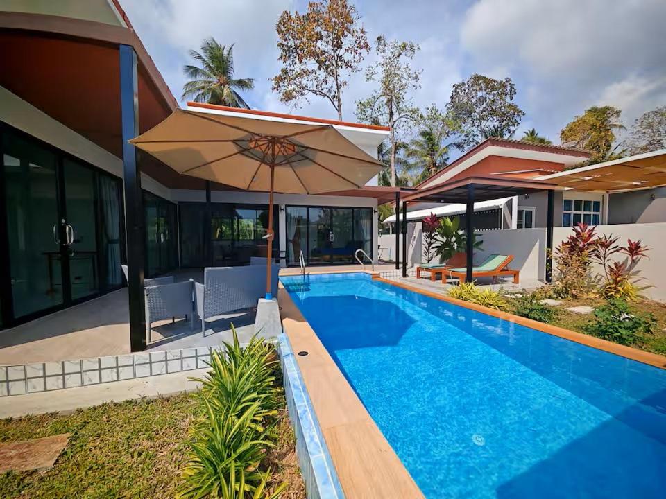 a house with a swimming pool and an umbrella at Beautiful accommodation on Lipa Noi in Nathon Bay